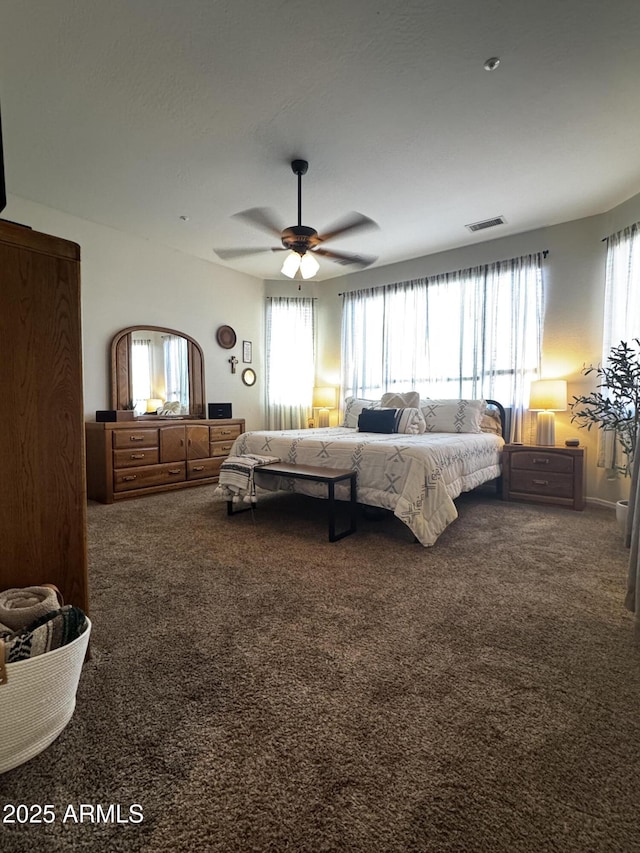 carpeted bedroom featuring a ceiling fan and visible vents