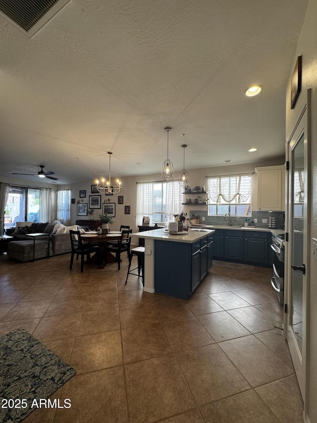 kitchen featuring a textured ceiling, a center island, gas range, open floor plan, and light countertops