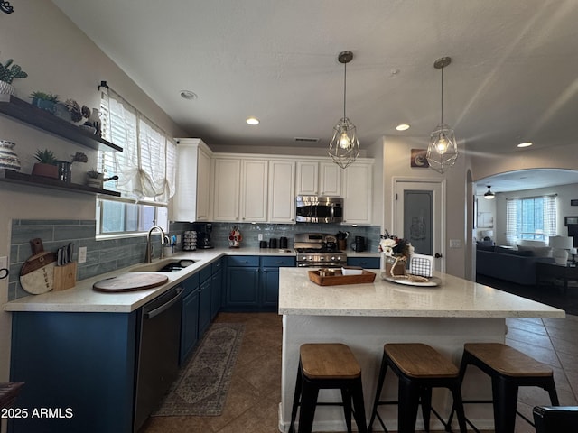 kitchen featuring appliances with stainless steel finishes, decorative backsplash, blue cabinets, and a sink