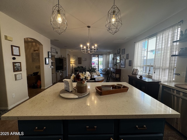 kitchen with decorative light fixtures, open floor plan, arched walkways, dark cabinets, and a kitchen island