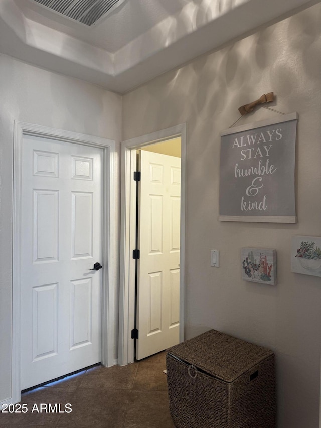 corridor featuring dark tile patterned flooring and visible vents