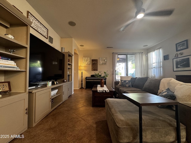 living area with dark tile patterned floors and a ceiling fan