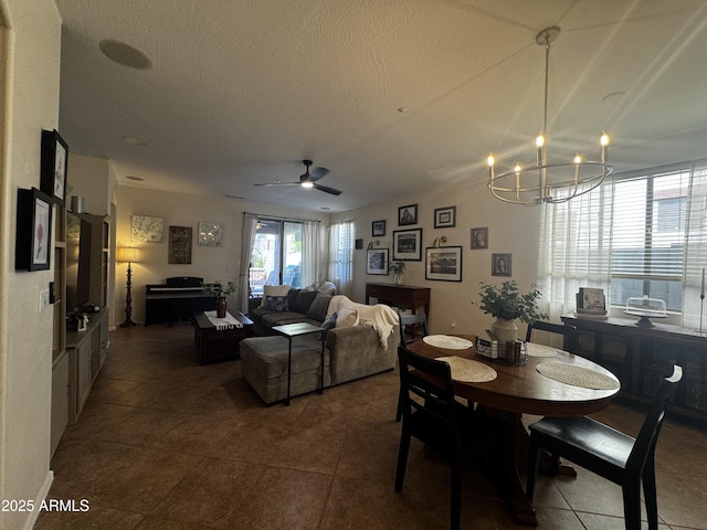 tiled dining space with a textured ceiling and ceiling fan with notable chandelier