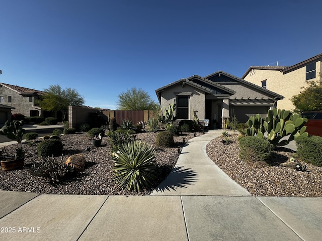 view of front of home with stucco siding, a tile roof, and fence