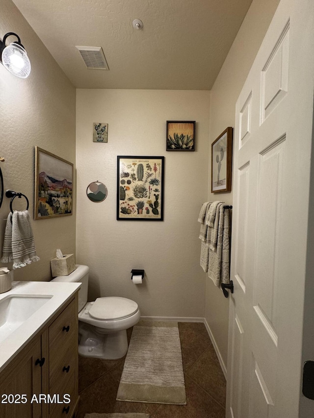 half bathroom featuring toilet, tile patterned floors, visible vents, baseboards, and vanity