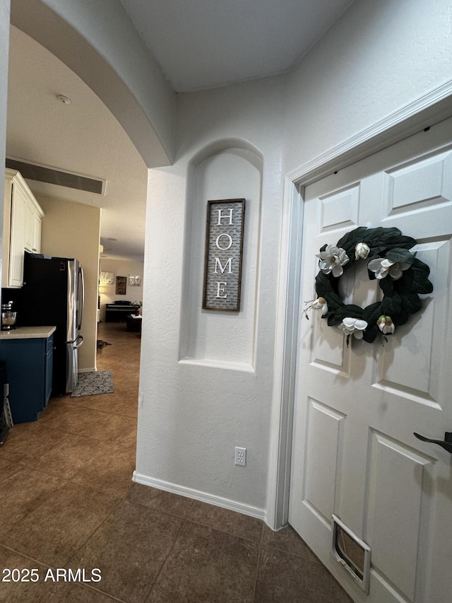 corridor featuring arched walkways, baseboards, and visible vents