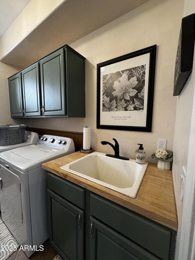 clothes washing area with a sink, separate washer and dryer, and cabinet space