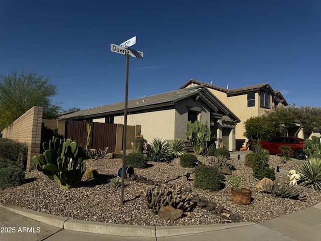 view of side of property with a hot tub, fence, and stucco siding
