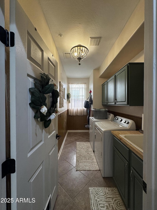 washroom featuring a sink, cabinet space, dark tile patterned floors, visible vents, and washing machine and clothes dryer