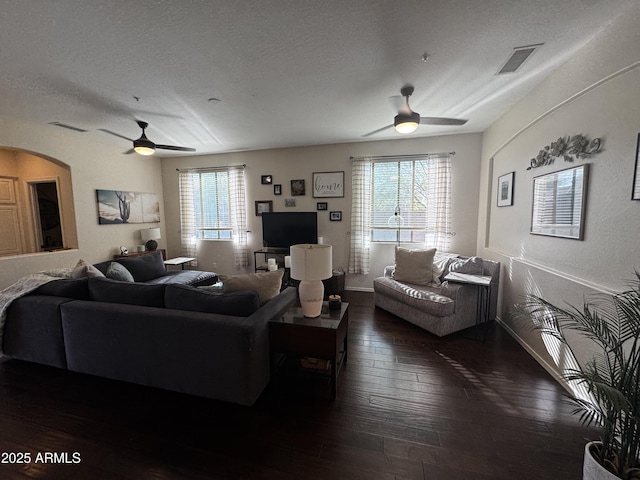 living area featuring dark wood-style flooring, a textured ceiling, a ceiling fan, and visible vents