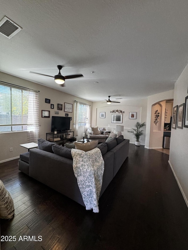 living room with a textured ceiling, visible vents, a ceiling fan, and wood-type flooring