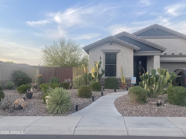 view of front of property with stone siding, stucco siding, and fence