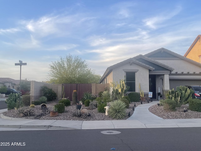 ranch-style house featuring stucco siding, an attached garage, and fence