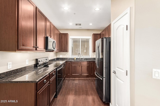 kitchen featuring dark stone countertops, sink, and appliances with stainless steel finishes