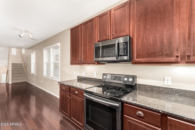 kitchen with dark hardwood / wood-style floors, dark stone countertops, stainless steel appliances, and track lighting