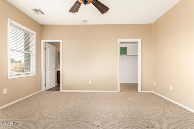 unfurnished bedroom with carpet, ceiling fan, a spacious closet, and a closet