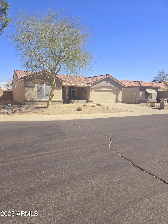 view of front facade featuring a garage, driveway, a tiled roof, and stucco siding