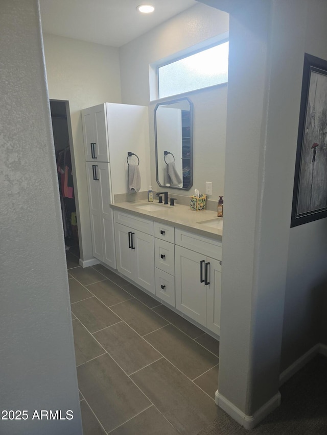 bathroom featuring double vanity, baseboards, a sink, and tile patterned floors