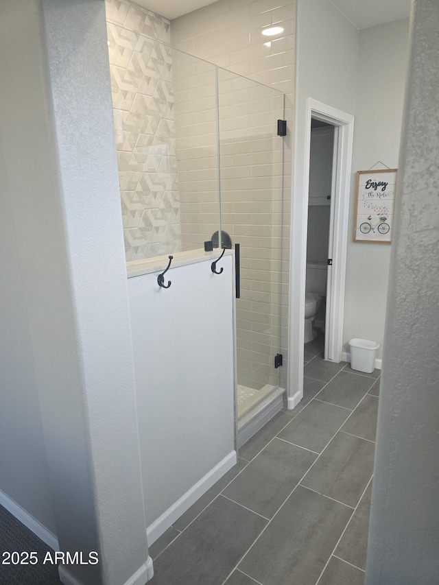 full bath with a stall shower, baseboards, toilet, and tile patterned floors