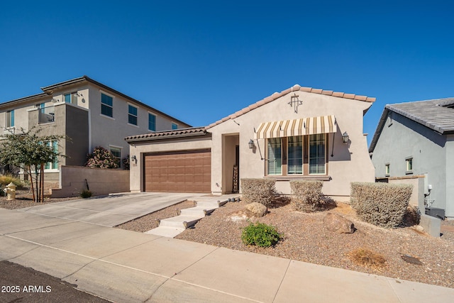 mediterranean / spanish house with a garage, concrete driveway, a tile roof, and stucco siding