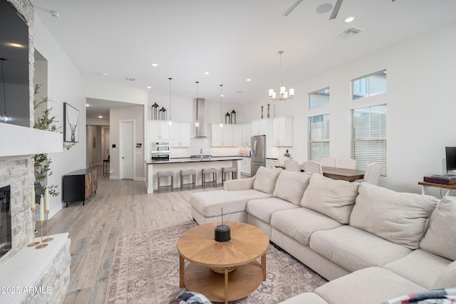 living room with light wood-style flooring, a fireplace, visible vents, and recessed lighting