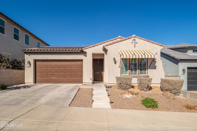 mediterranean / spanish-style house with a garage, concrete driveway, a tiled roof, roof mounted solar panels, and stucco siding