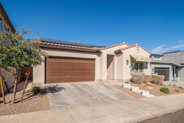 mediterranean / spanish house featuring stucco siding, concrete driveway, an attached garage, roof mounted solar panels, and fence