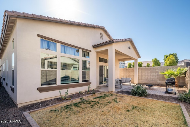 rear view of property with a patio area, fence, and stucco siding