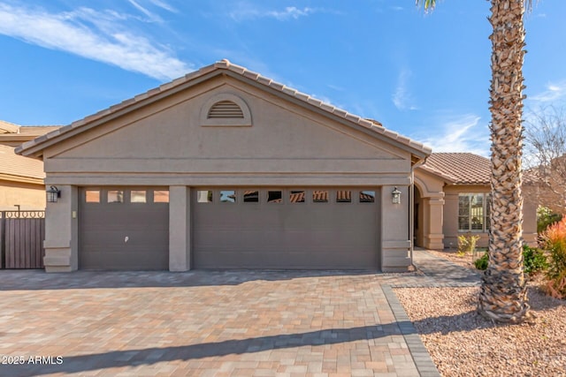 view of front of property featuring a garage, decorative driveway, a tile roof, and stucco siding