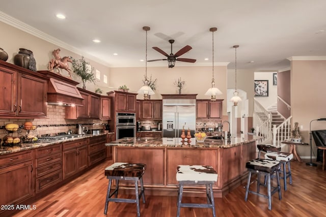 kitchen with stainless steel appliances, a breakfast bar area, pendant lighting, and custom exhaust hood