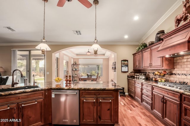 kitchen featuring arched walkways, stainless steel appliances, visible vents, hanging light fixtures, and a sink