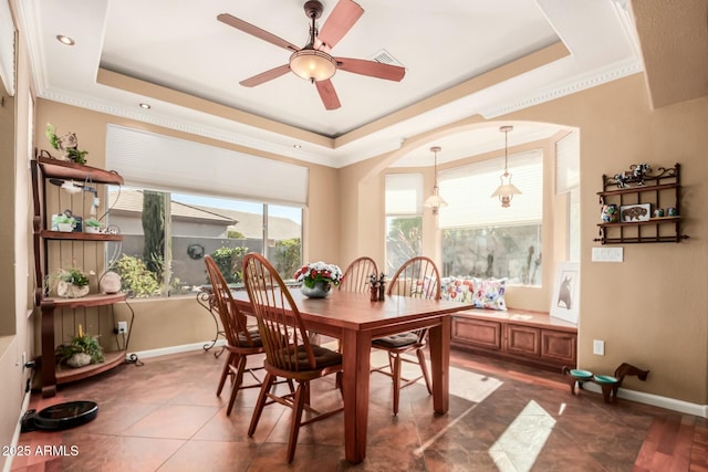 dining area featuring ornamental molding, a raised ceiling, and baseboards