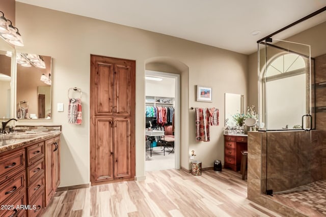 full bath featuring a shower stall, baseboards, wood finished floors, and vanity