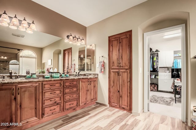 bathroom with double vanity, visible vents, wood finished floors, a spacious closet, and a sink