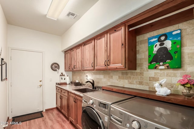 washroom featuring washer and clothes dryer, cabinet space, visible vents, light wood-style floors, and a sink