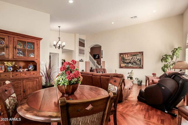 dining area featuring visible vents, arched walkways, light wood-style flooring, an inviting chandelier, and recessed lighting