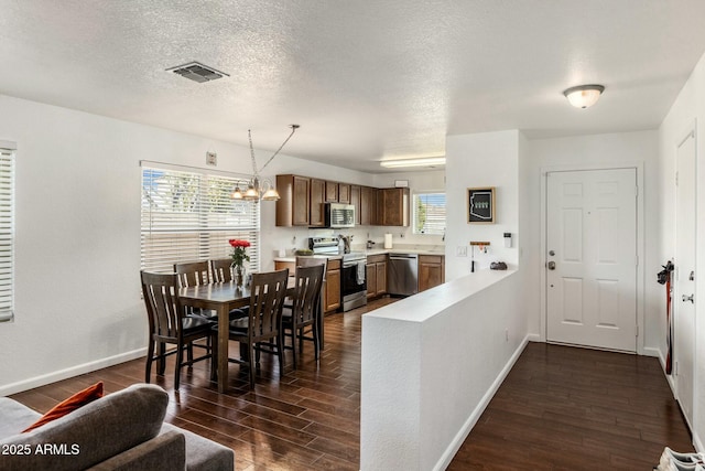 dining area featuring a textured ceiling, dark hardwood / wood-style floors, and a chandelier