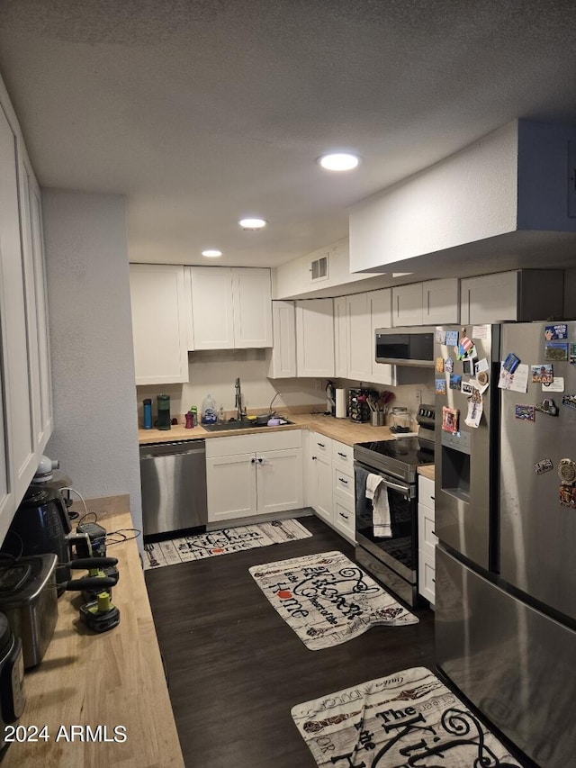 kitchen with white cabinets, sink, a textured ceiling, stainless steel appliances, and light hardwood / wood-style floors