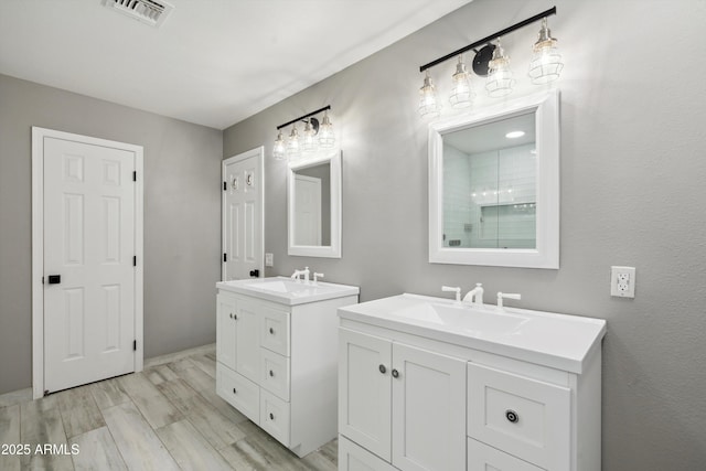 full bath featuring visible vents, wood finished floors, two vanities, and a sink