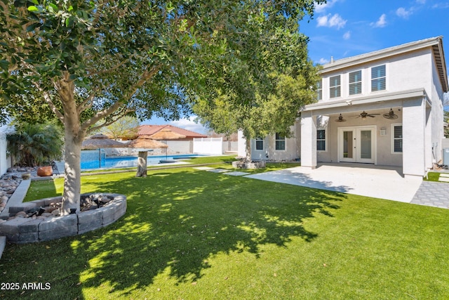 rear view of property with fence, french doors, a lawn, and ceiling fan