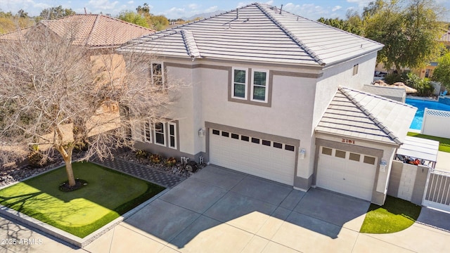 view of front of house with a tile roof, concrete driveway, fence, and stucco siding