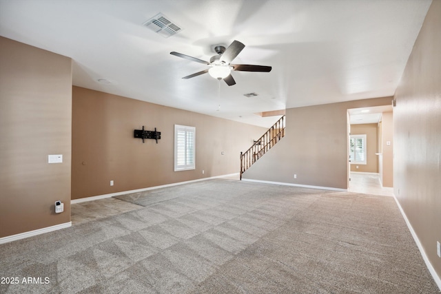 unfurnished living room featuring stairway, carpet, visible vents, and a healthy amount of sunlight