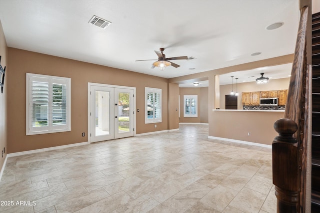 unfurnished living room with visible vents, baseboards, and a ceiling fan