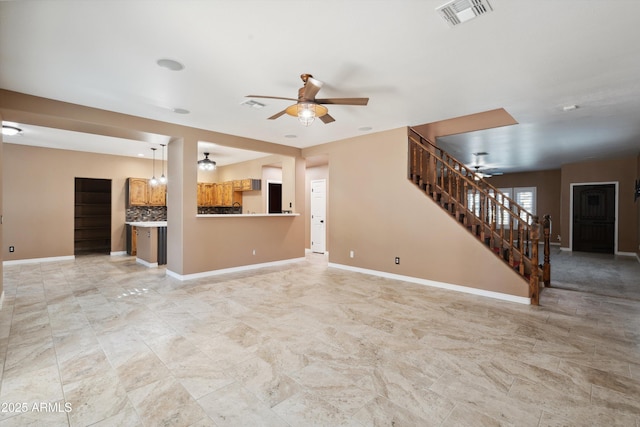 unfurnished living room with stairs, baseboards, visible vents, and ceiling fan