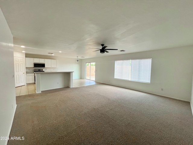 unfurnished living room featuring light colored carpet and ceiling fan