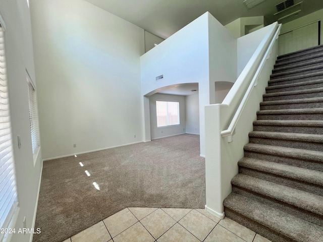 staircase featuring a towering ceiling and tile patterned flooring