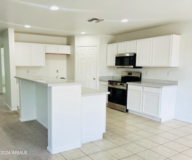 kitchen featuring stainless steel appliances, white cabinetry, a center island, and light stone counters