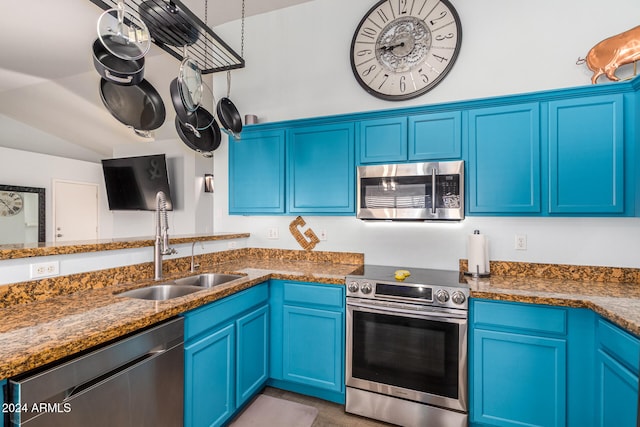 kitchen with stainless steel appliances, blue cabinets, dark stone counters, and sink