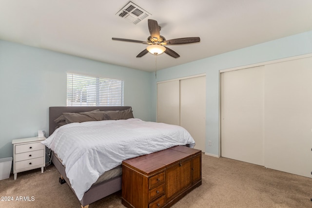 carpeted bedroom featuring ceiling fan and multiple closets