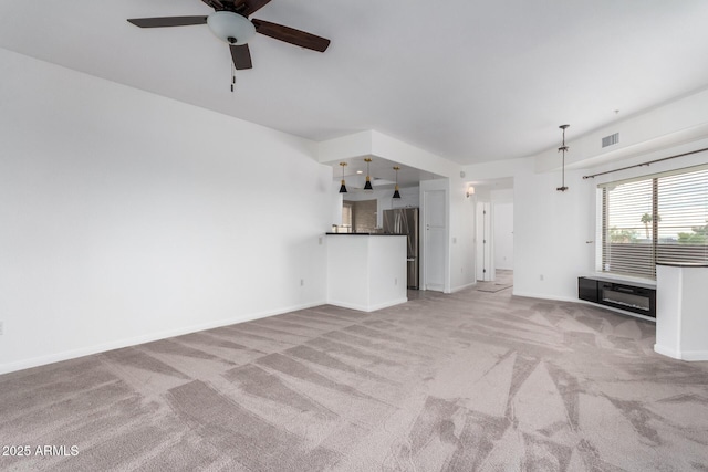 unfurnished living room featuring light carpet and ceiling fan